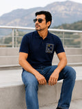 Man in navy blue Calvin Klein polo shirt and blue jeans wearing sunglasses outdoors.