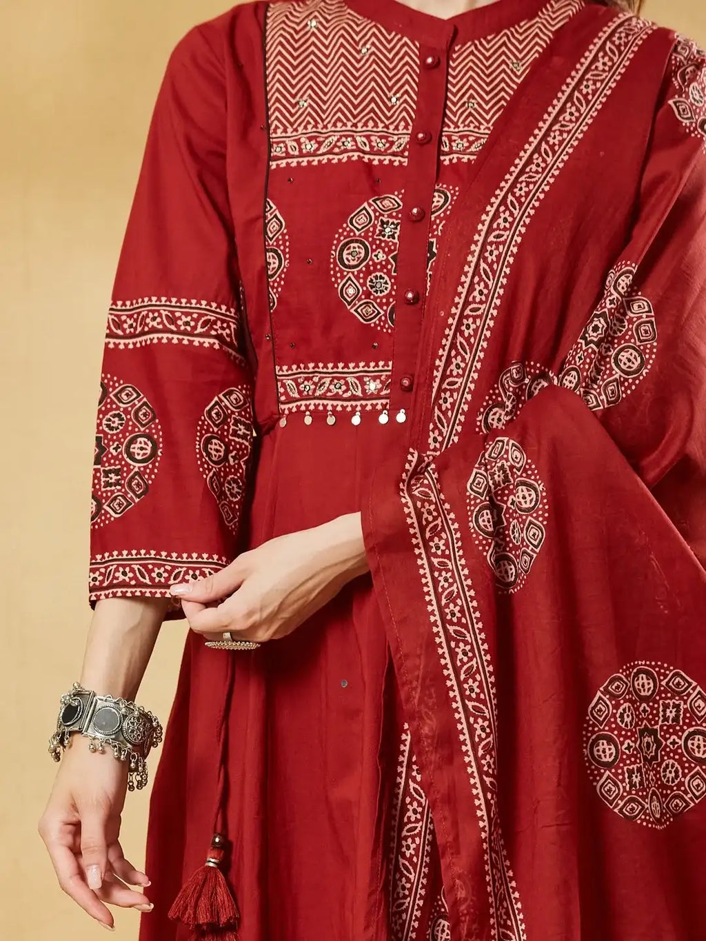 Woman wearing a red Indian ethnic dress with traditional prints and oxidized silver jewelry.