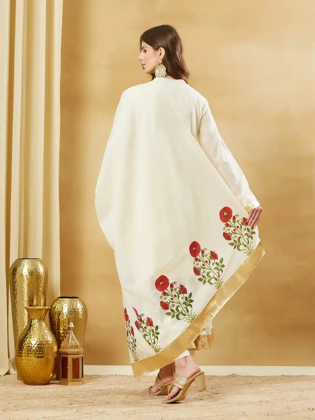 Woman in elegant white silk saree with red floral embroidery and gold border