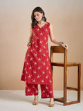Woman wearing a red sleeveless printed kurta and palazzo set with ethnic jewelry.
