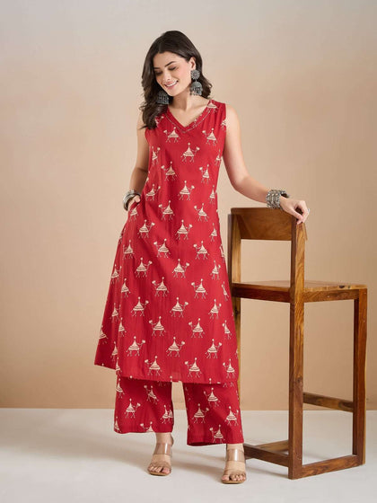 Woman wearing a red sleeveless printed kurta and palazzo set with ethnic jewelry.