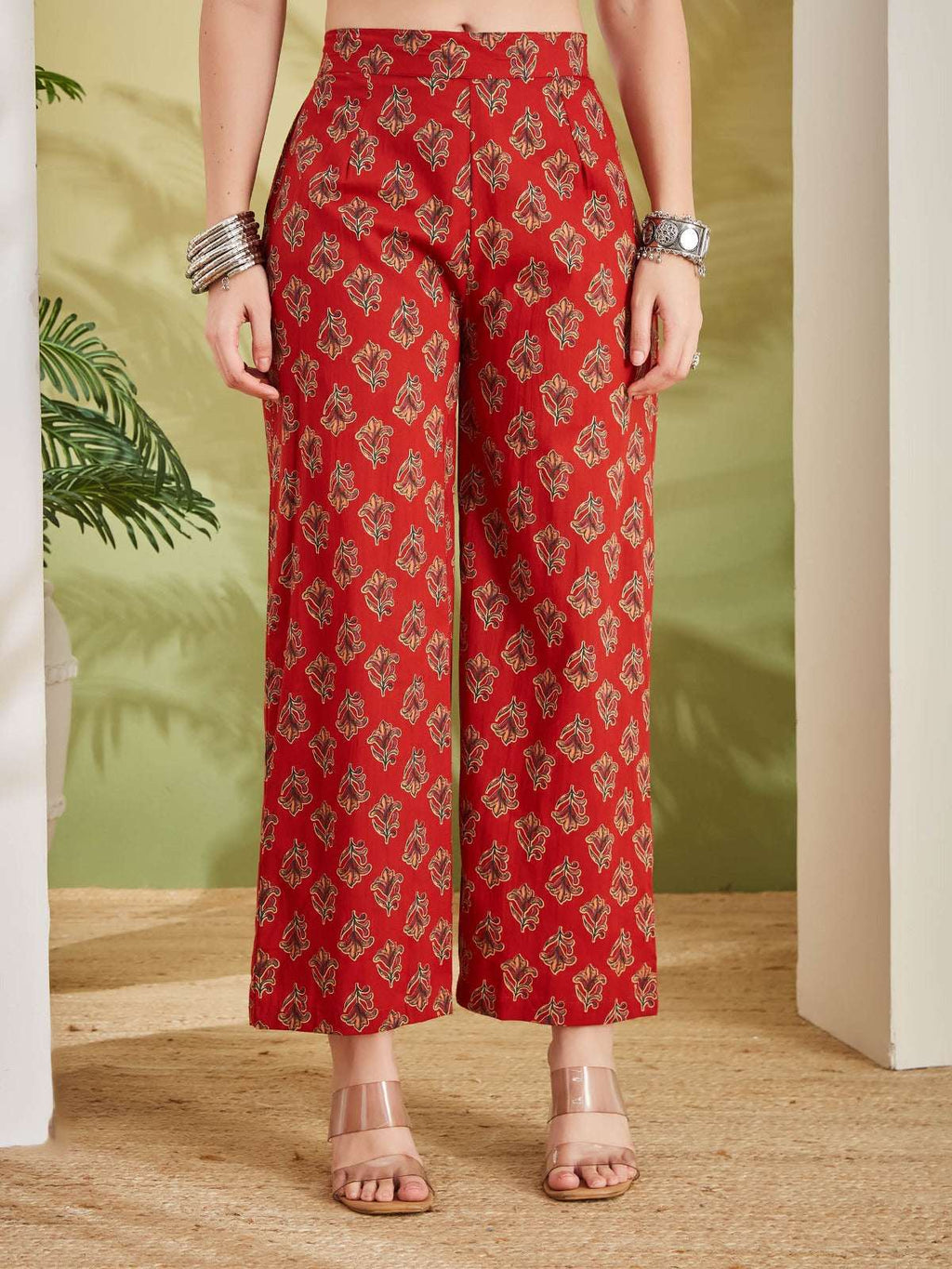 Woman wearing red wide-leg palazzo pants with gold ethnic floral print.