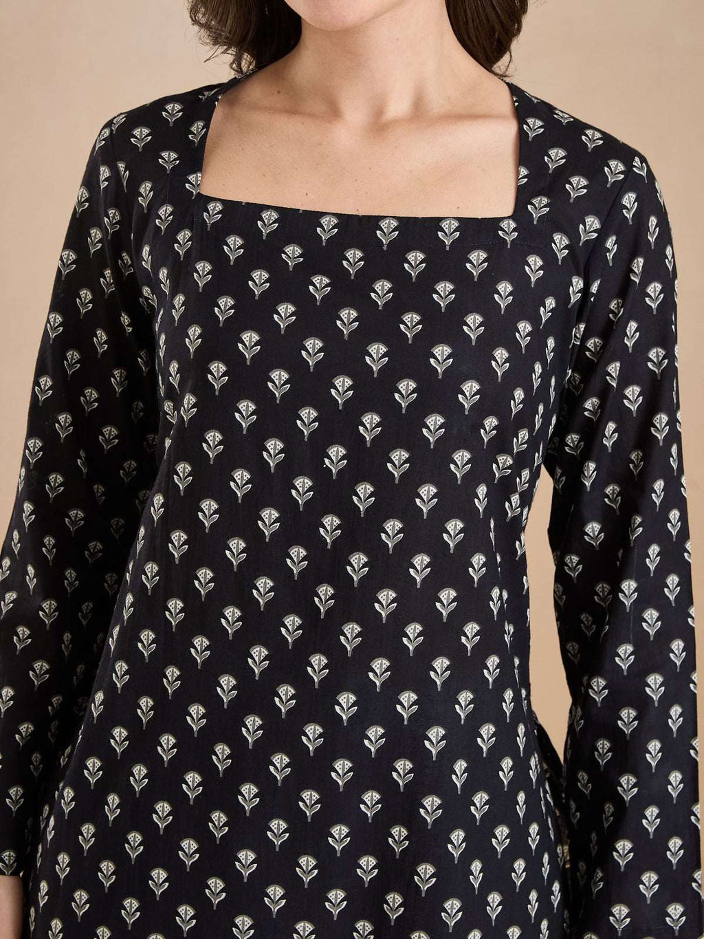 Woman wearing a black Indian ethnic tunic with white floral block print and square neckline.
