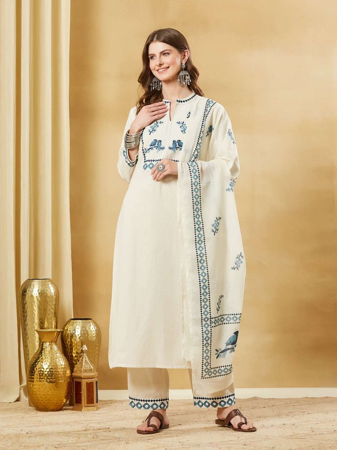 Woman wearing an off-white Indian ethnic kurta set with blue floral embroidery and matching dupatta
