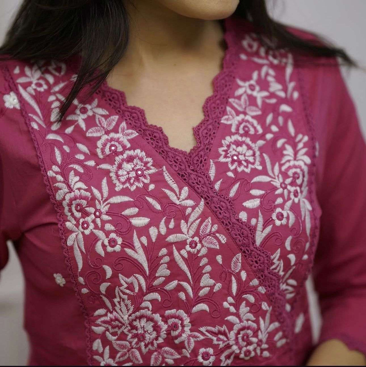 Pink ethnic tunic featuring intricate white floral embroidery and a scalloped V-neckline.