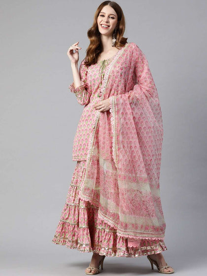 Woman wearing a pink printed ethnic sharara suit with a matching dupatta