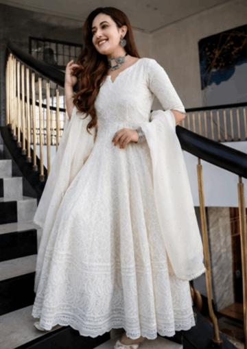 Woman wearing an elegant white embroidered Anarkali suit with a matching dupatta.