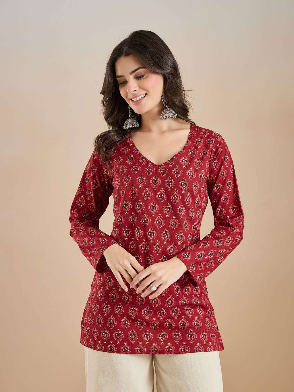 Woman wearing a red printed V-neck ethnic tunic with traditional Indian patterns.