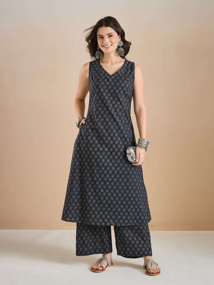 Woman wearing a navy blue printed sleeveless kurta and palazzo set with silver jewelry.
