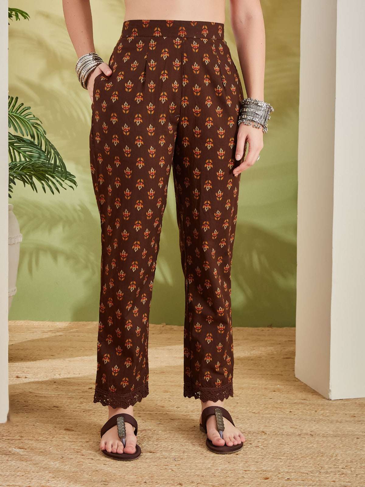 Woman wearing brown ethnic printed trousers with lace hem and traditional silver bangles.
