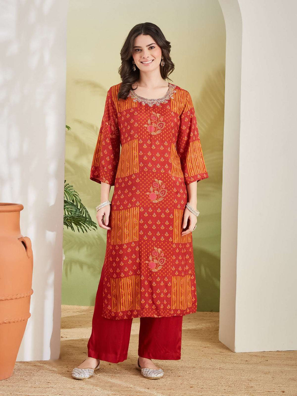 Woman wearing a red and orange printed ethnic kurta with matching palazzo pants.