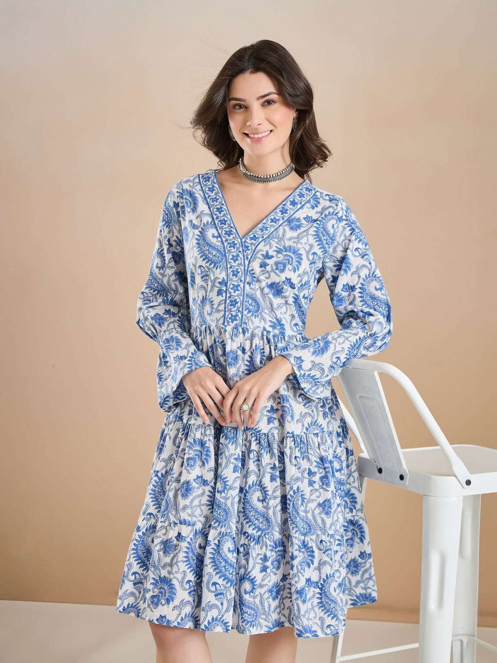 Woman wearing a blue and white floral print Indian ethnic cotton dress with long sleeves.