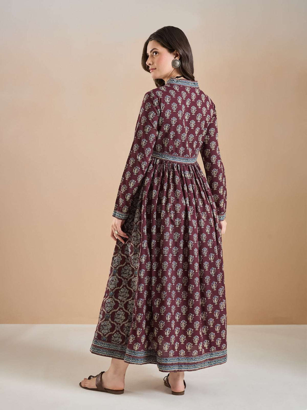 Woman wearing a maroon floral print Indian ethnic maxi dress with long sleeves.