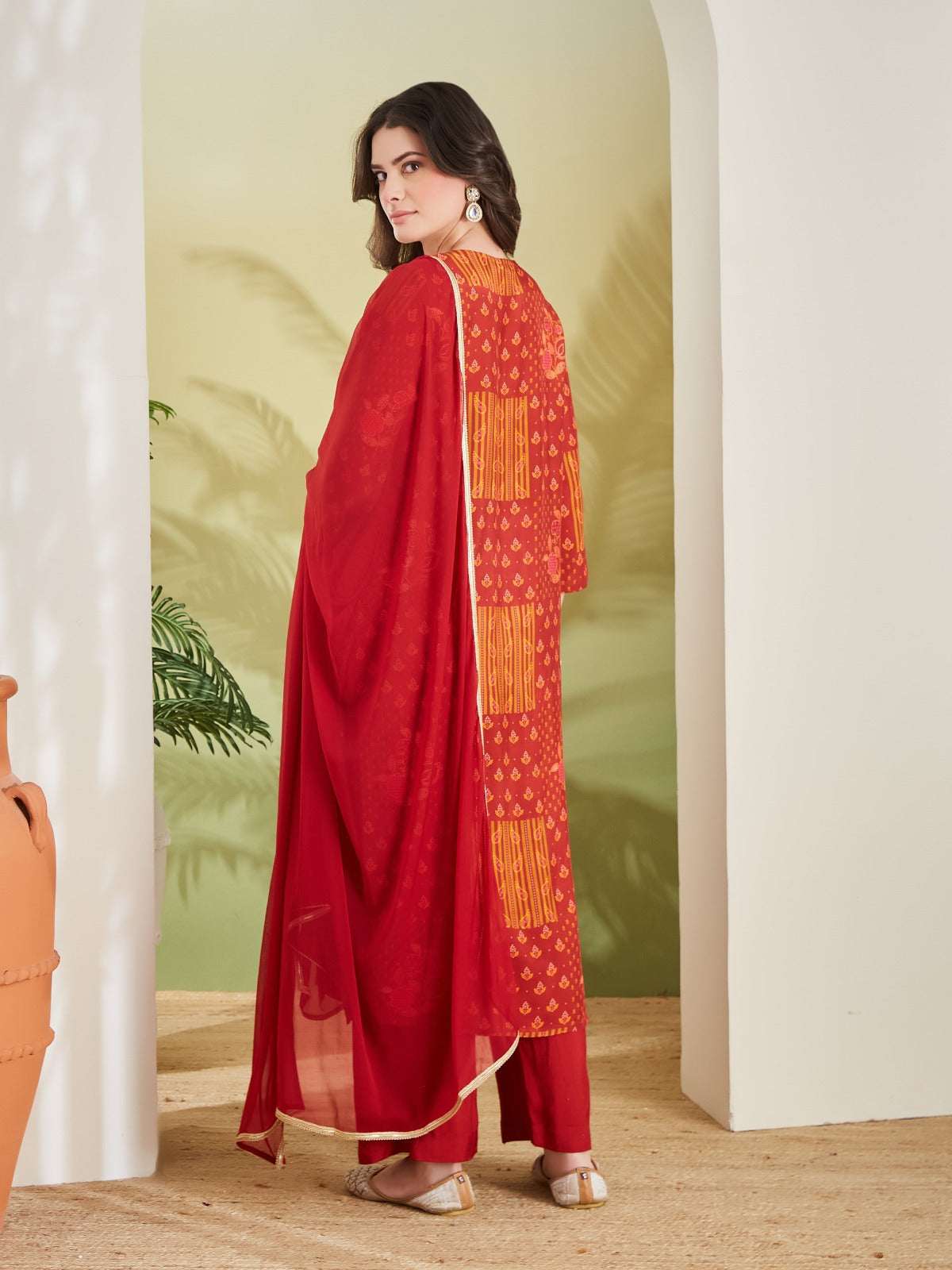 Woman wearing a red printed ethnic kurta with matching dupatta and trousers.