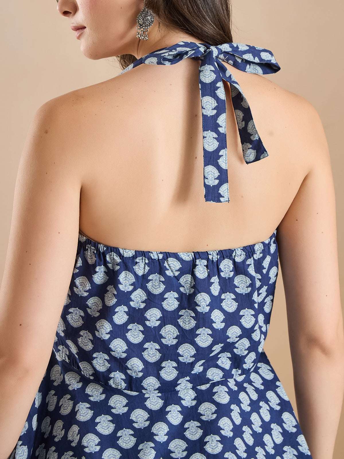 Woman wearing a blue floral print halter neck ethnic dress with a back tie detail.