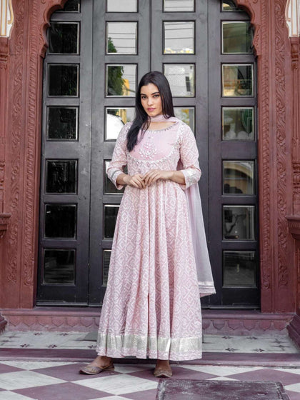 Woman wearing a light pink patterned Anarkali suit with silver embroidery and dupatta.