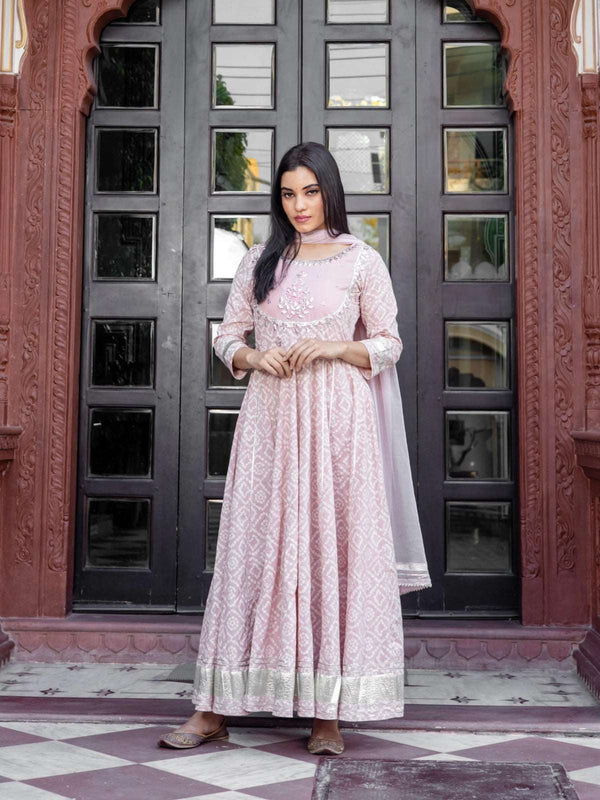 Woman wearing a light pink patterned Anarkali suit with silver embroidery and dupatta.
