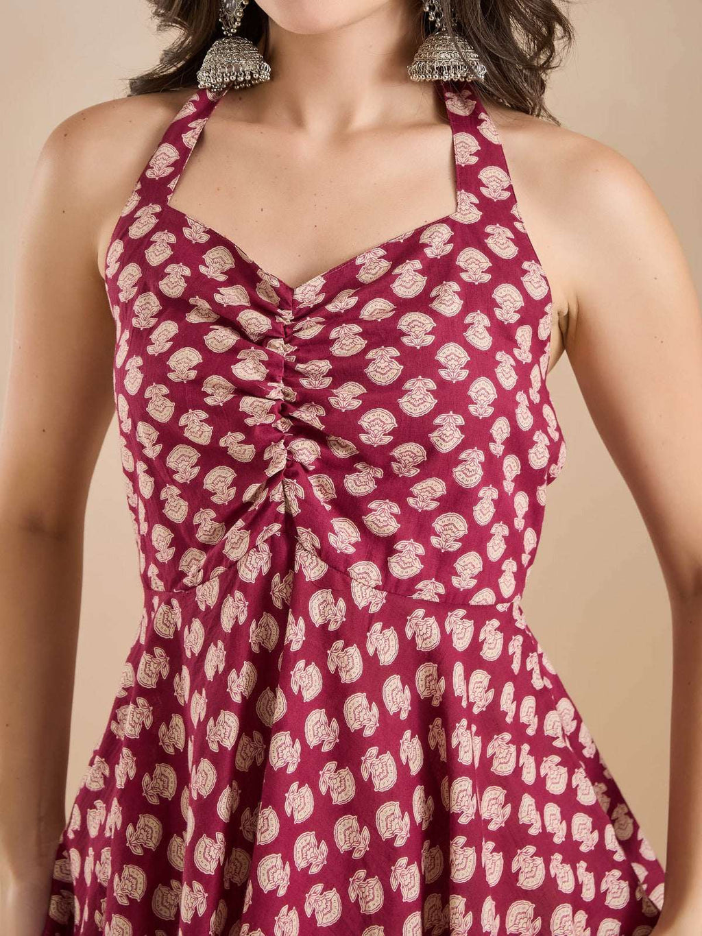 Woman wearing a maroon halter neck ethnic dress with cream floral print.