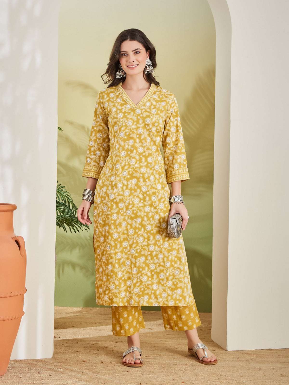 Woman wearing a yellow floral print cotton kurta set with matching trousers.