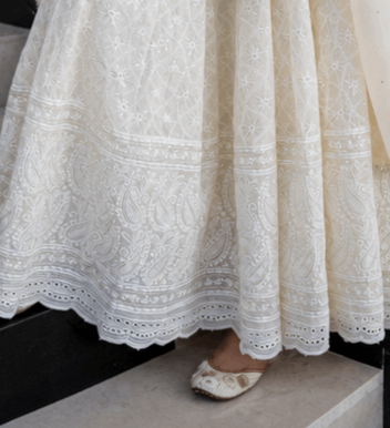 Cream colored ethnic lehenga skirt with intricate white embroidery and scalloped hem.