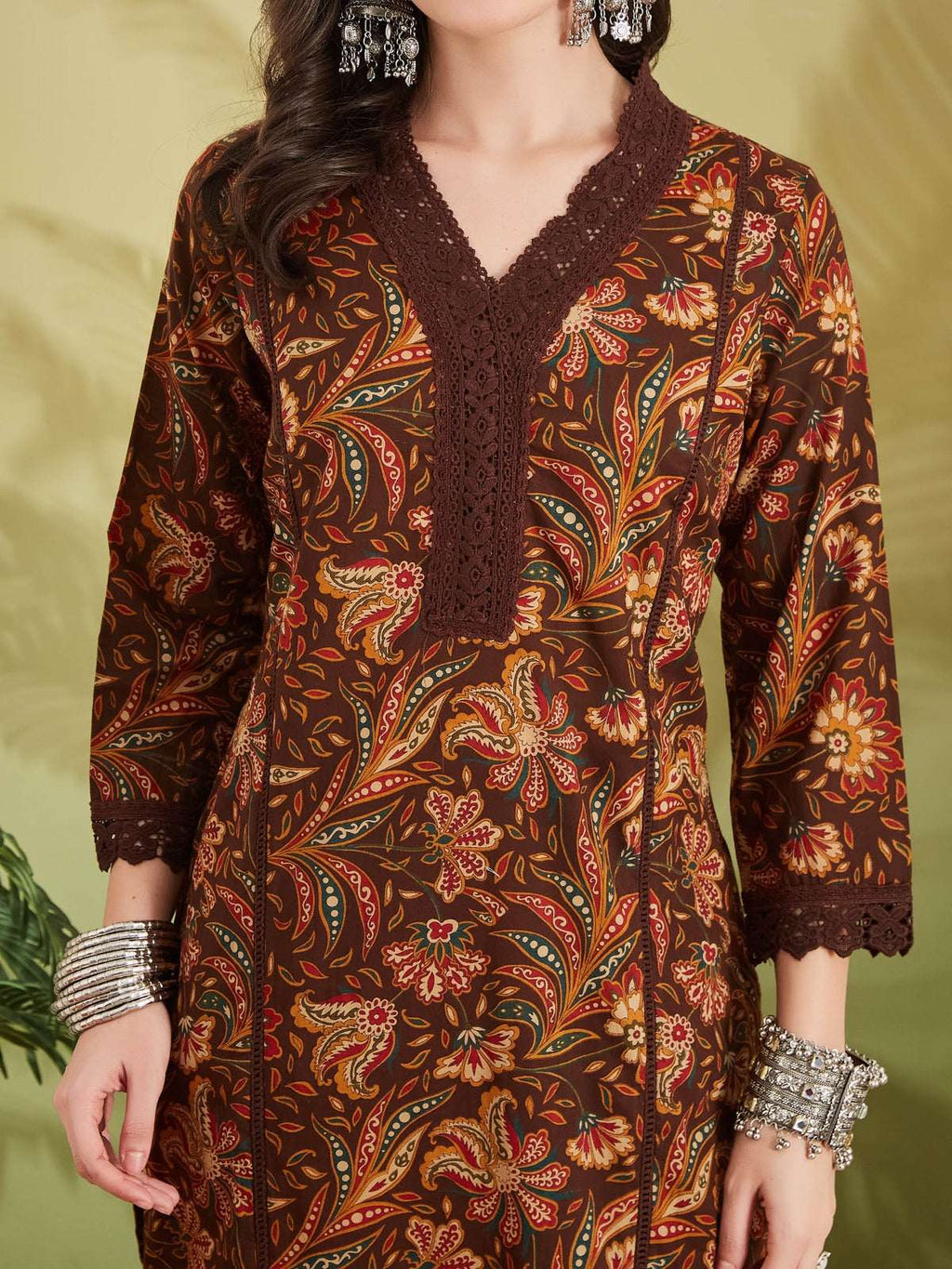 Woman wearing a brown floral print ethnic kurta with lace detailing and silver bangles.