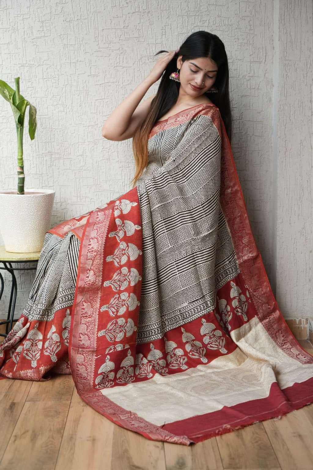Woman wearing an elegant black and white striped saree with a red floral border.