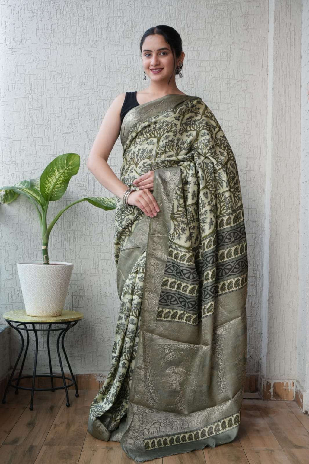 Woman wearing an elegant olive green Banarasi silk saree with intricate gold floral patterns.