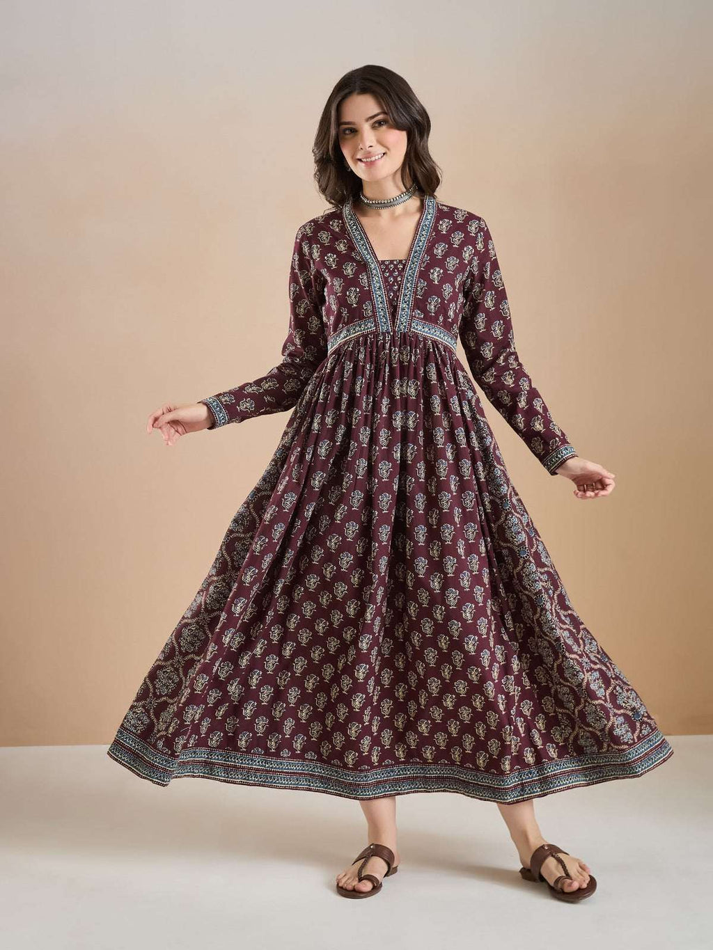 Woman wearing a maroon floral print long ethnic Anarkali dress with long sleeves.