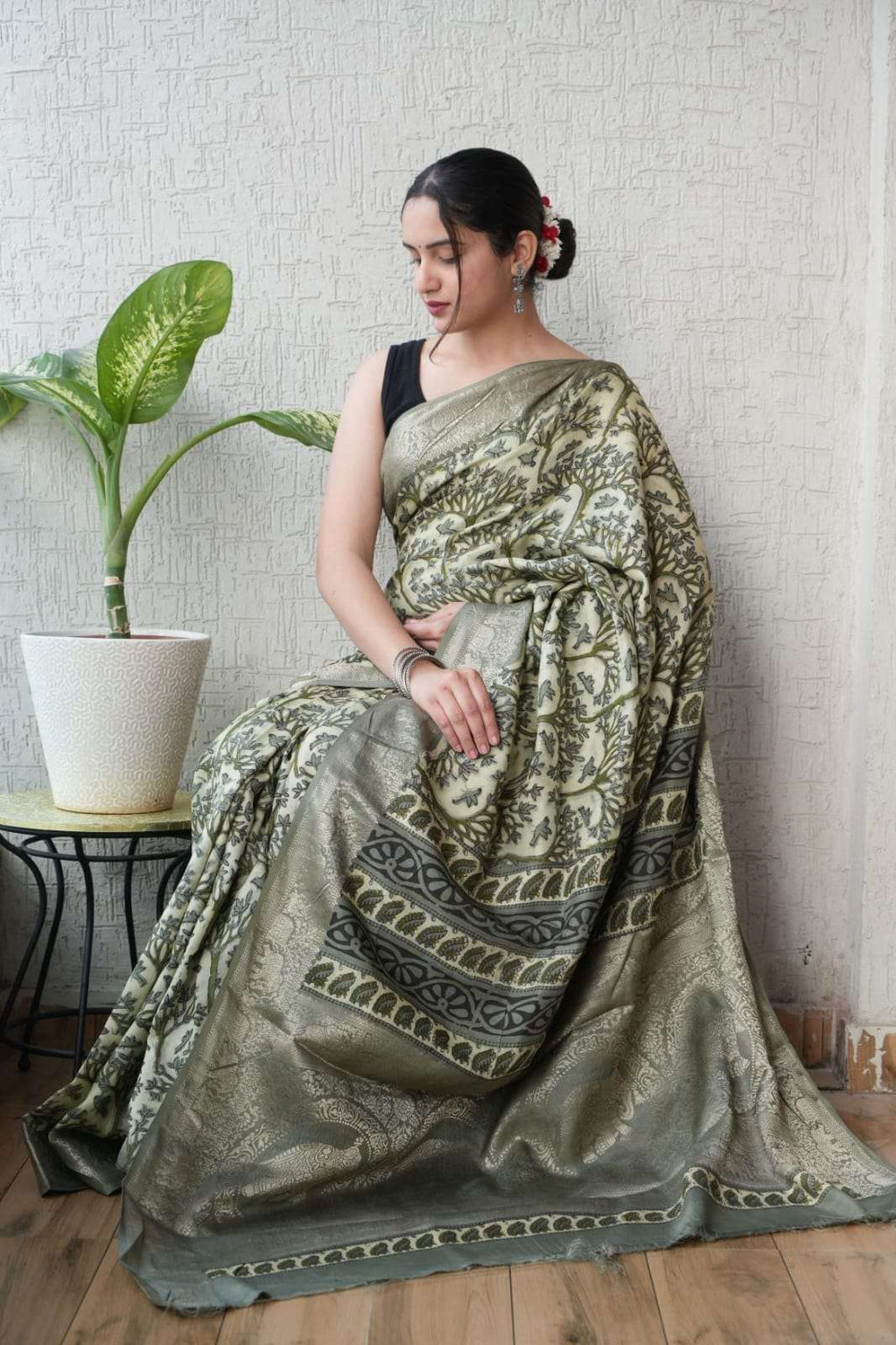 Woman wearing an elegant sage green Banarasi silk saree with intricate gold zari floral patterns.
