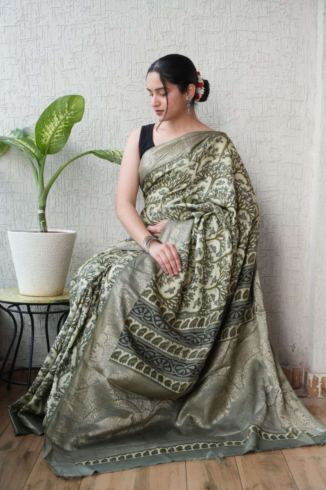 Woman wearing an elegant sage green Banarasi silk saree with intricate gold zari floral patterns.