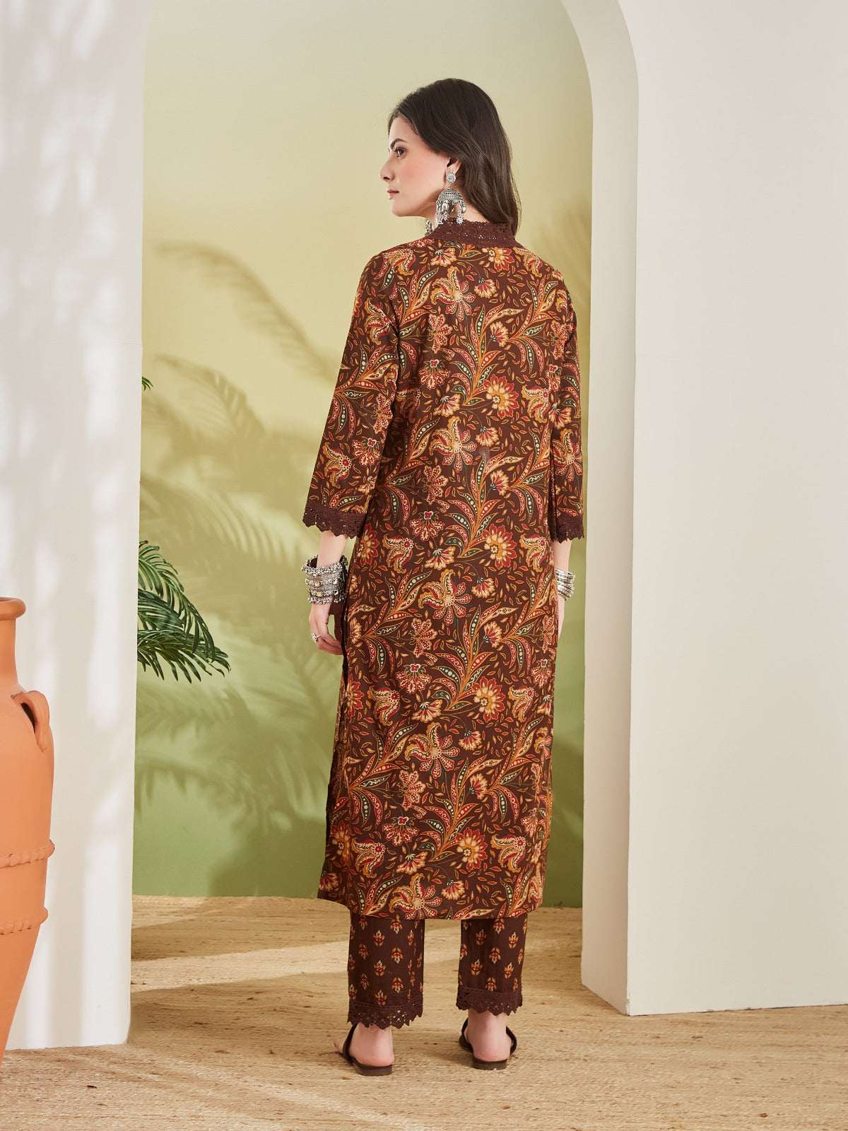 Woman wearing a brown floral print ethnic kurta and matching trousers set.