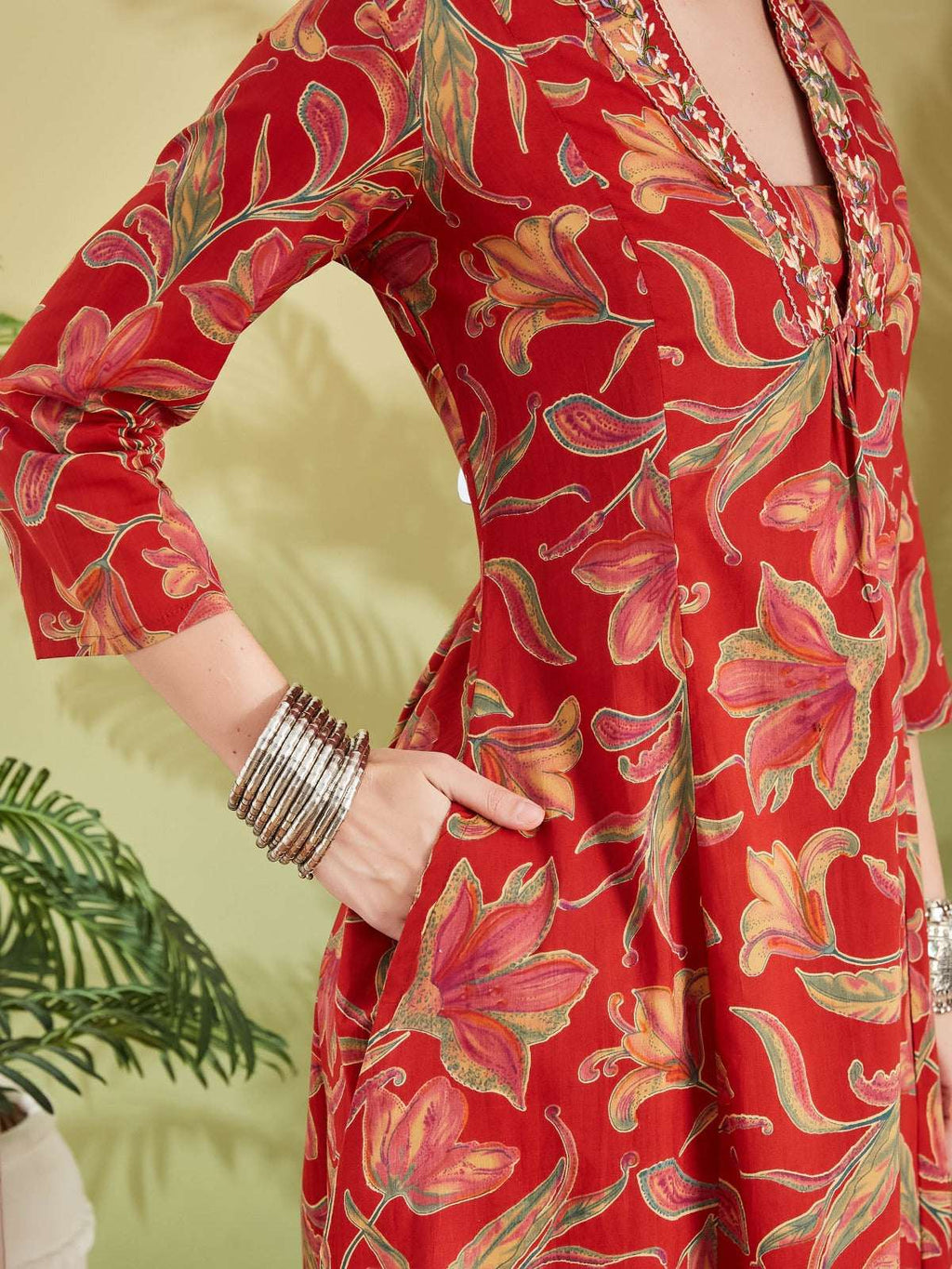 Red floral print ethnic dress with long sleeves and intricate embroidery detail.