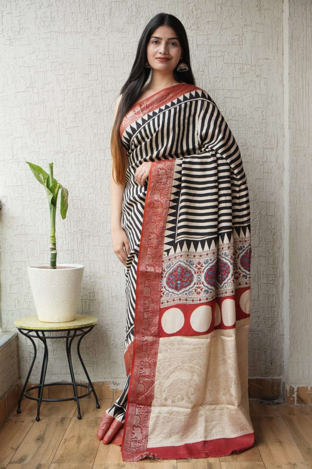 Woman wearing a black and white striped saree with a red and gold patterned border.