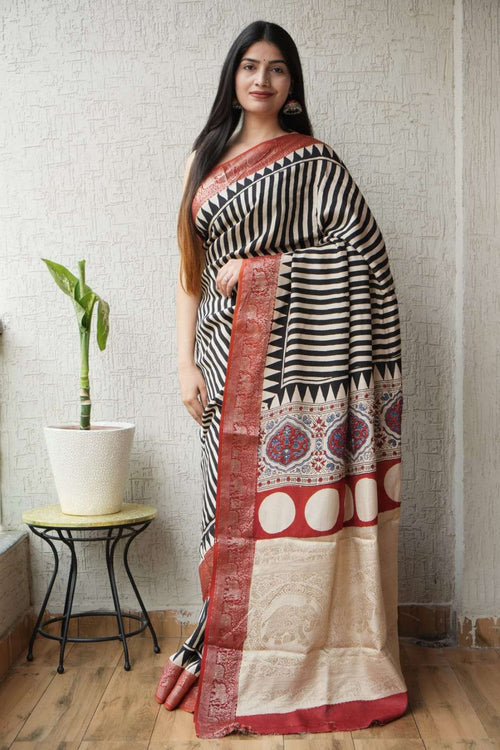 Woman wearing a black and white striped saree with a red and gold patterned border.