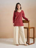 Woman wearing a red printed ethnic tunic with cream wide-leg palazzo pants.