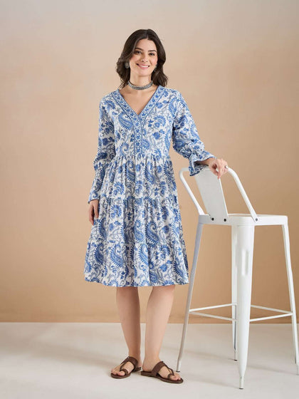 Woman wearing a blue and white floral print V-neck tiered summer dress.