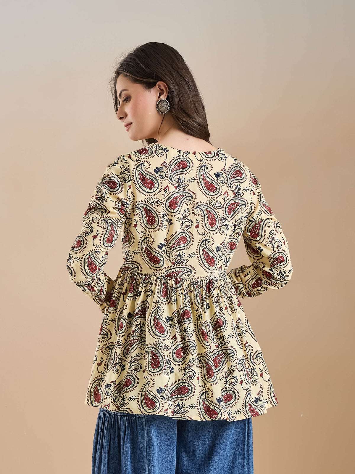 Woman wearing a cream paisley print ethnic peplum top with long sleeves.