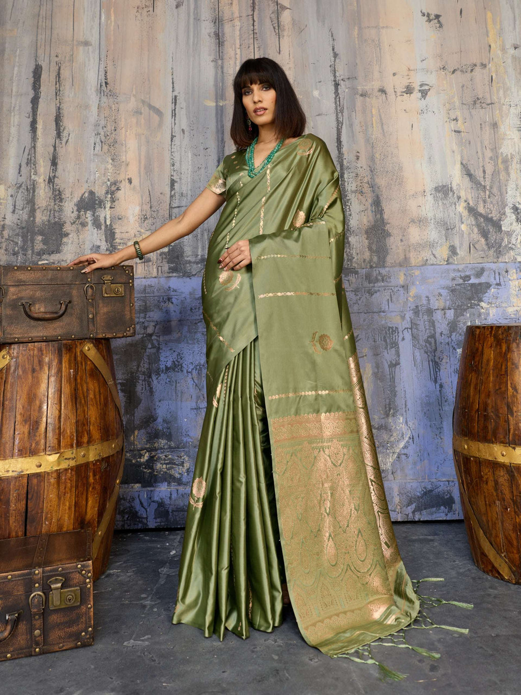 Woman in elegant olive green silk saree with gold zari border and traditional jewelry