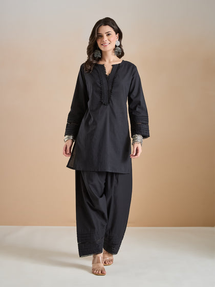 Woman wearing a black ethnic tunic with lace detailing and matching palazzo pants.