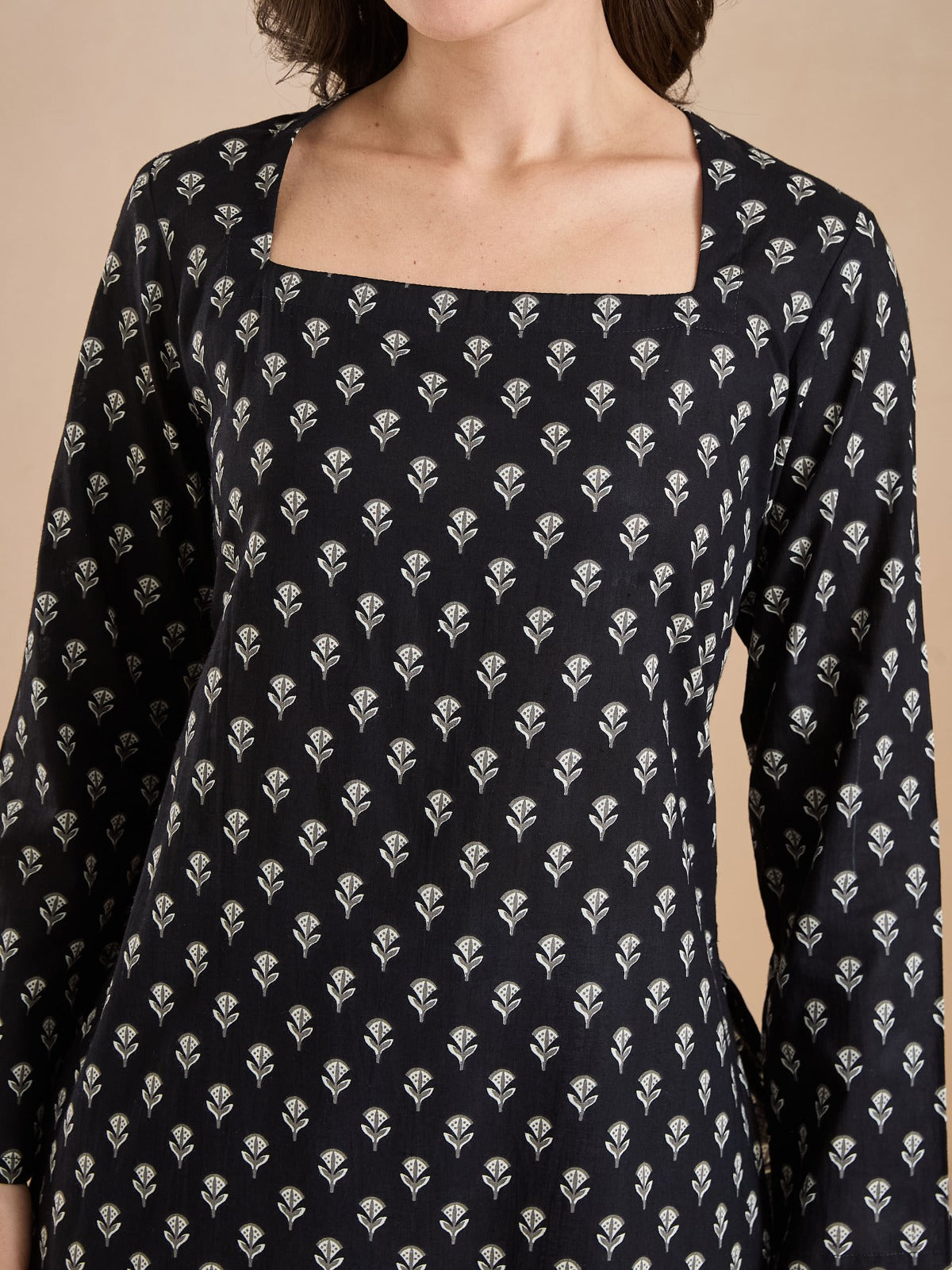 Woman wearing a black Indian ethnic tunic with white floral block print and square neckline.