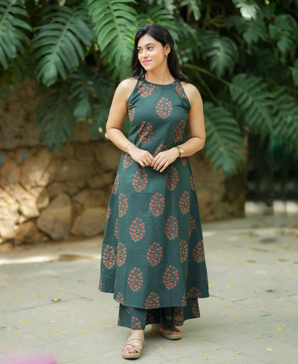 Woman wearing a dark green floral print sleeveless ethnic dress and matching pants.
