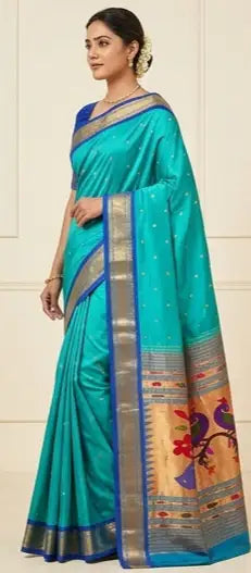 Woman wearing a turquoise blue silk saree with gold zari border and traditional motifs.