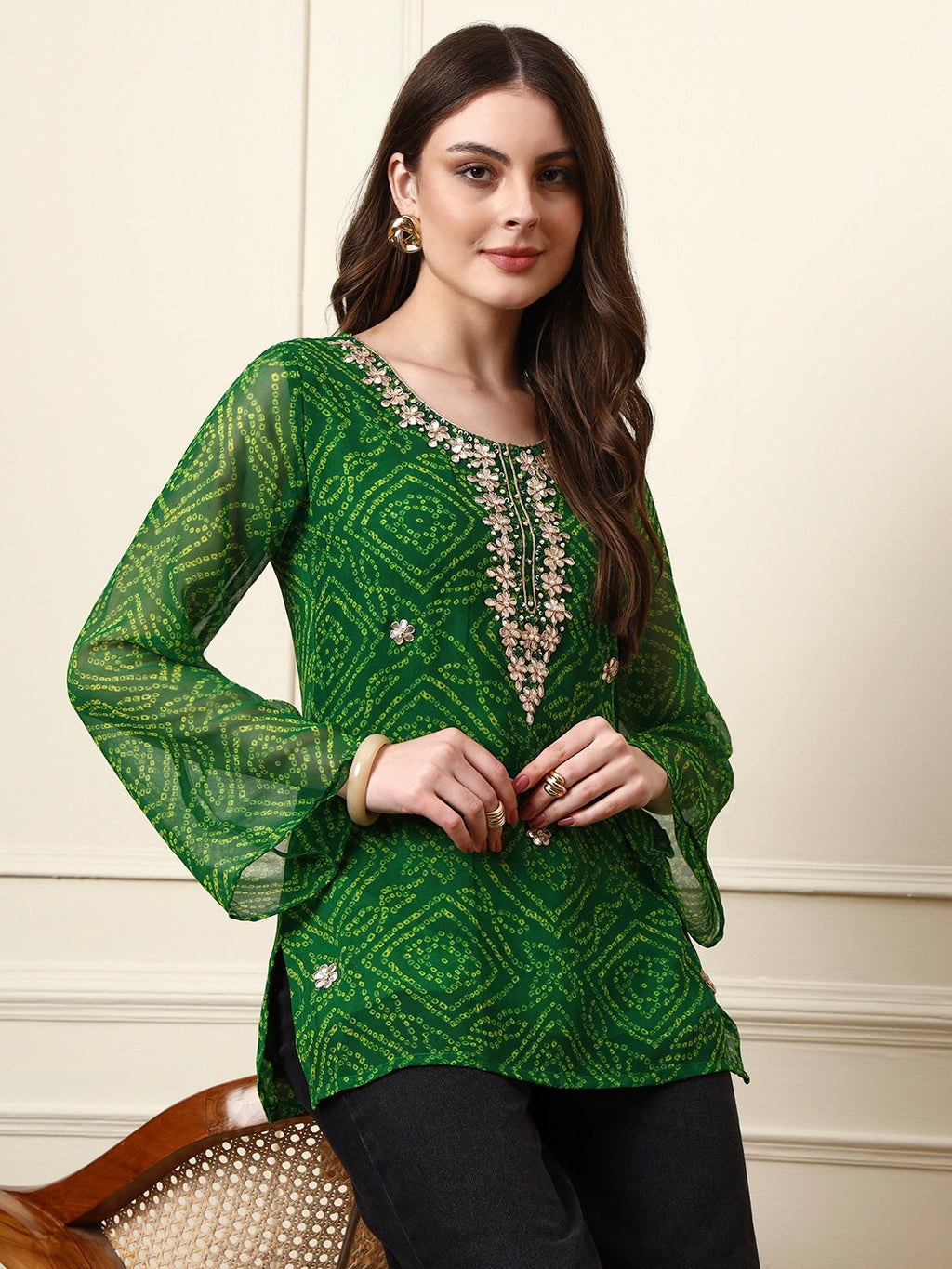 Woman wearing a green bandhani print tunic with floral embroidery and bell sleeves.