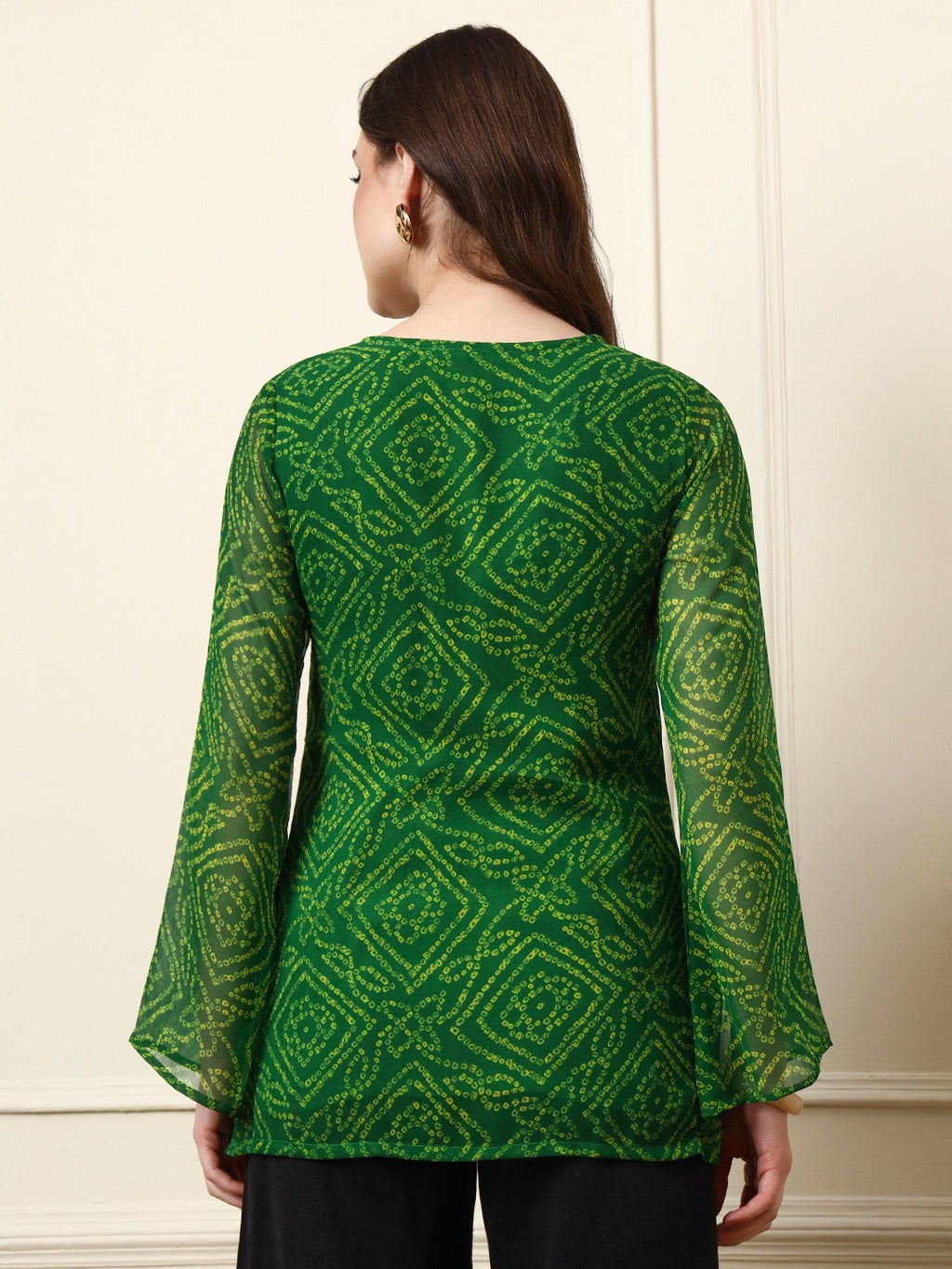 Woman wearing a green Bandhani print long sleeve tunic top with flared sleeves.