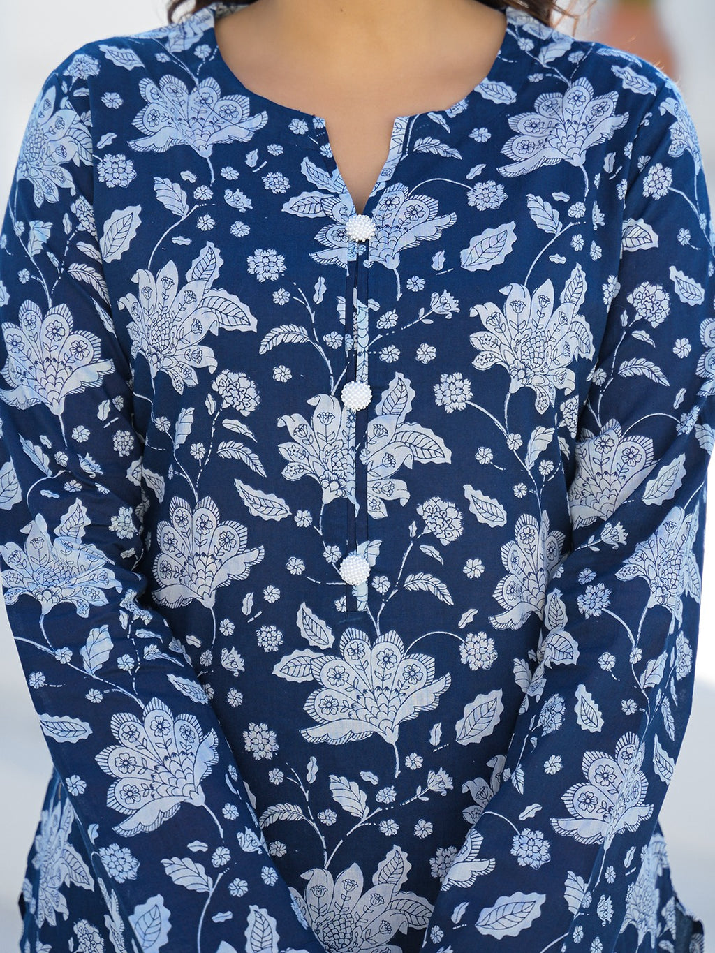 Woman wearing a navy blue floral print cotton ethnic kurta with white button details.