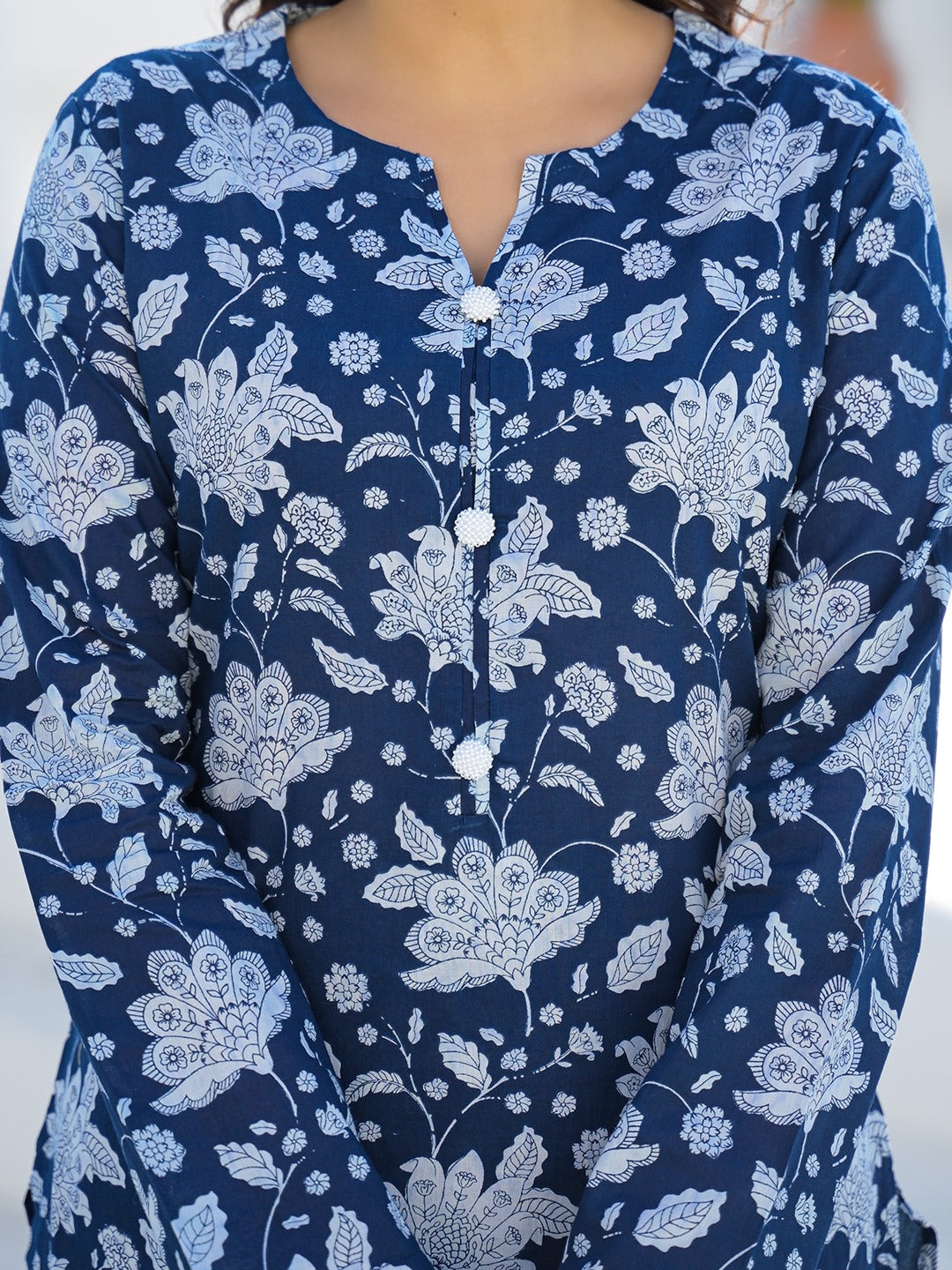 Woman wearing a navy blue floral print cotton ethnic kurta with white button details.