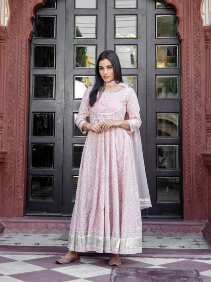 Woman wearing a light pink patterned Anarkali suit with silver embroidery and dupatta.