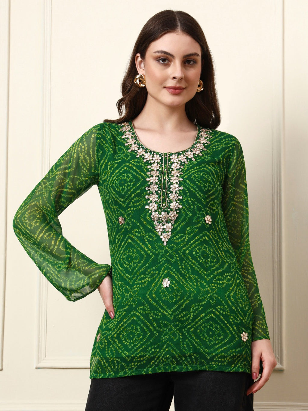 Woman wearing a green bandhani print tunic with floral embroidery and long sleeves.