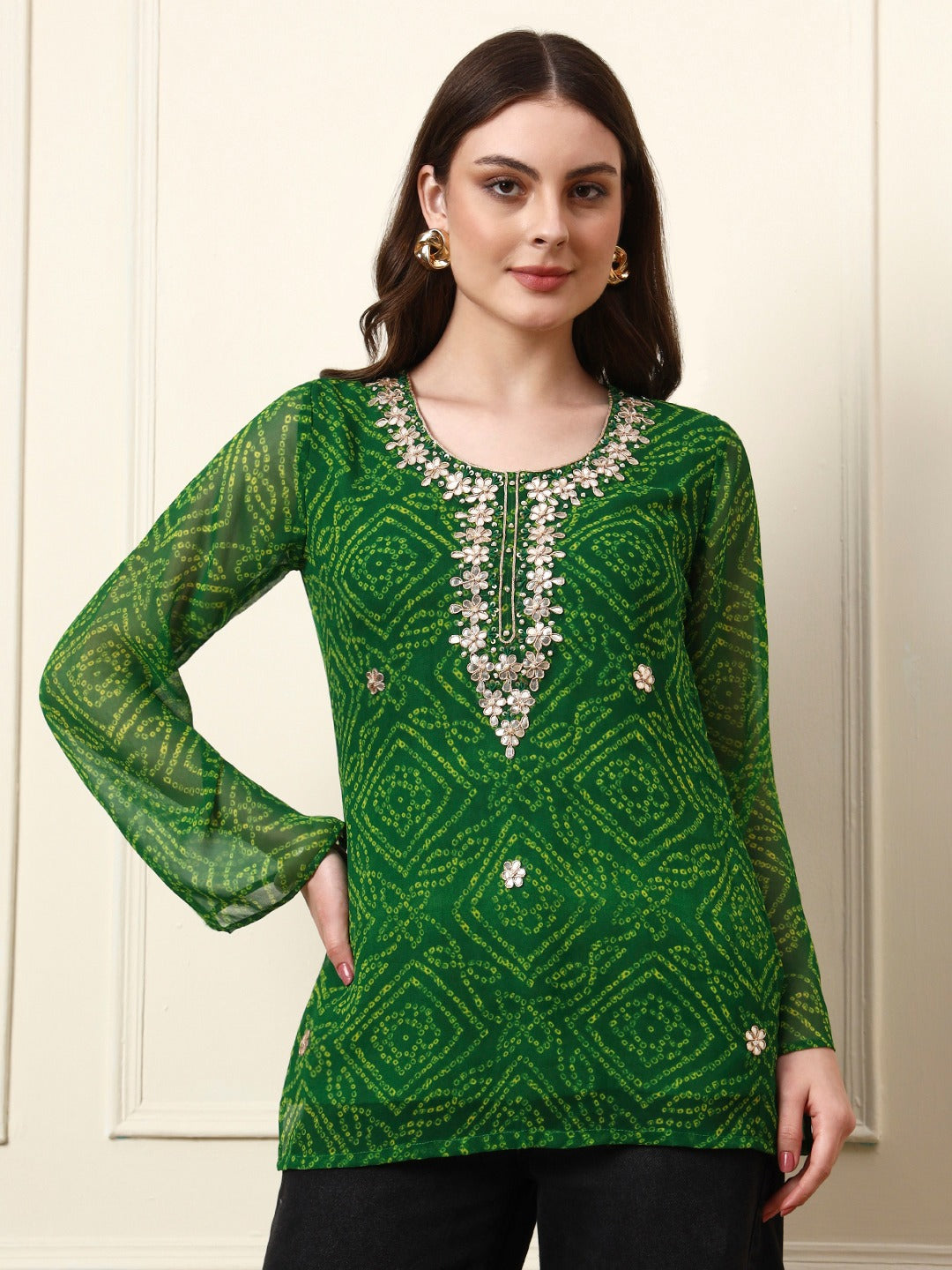Woman wearing a green bandhani print tunic with floral embroidery and long sleeves.