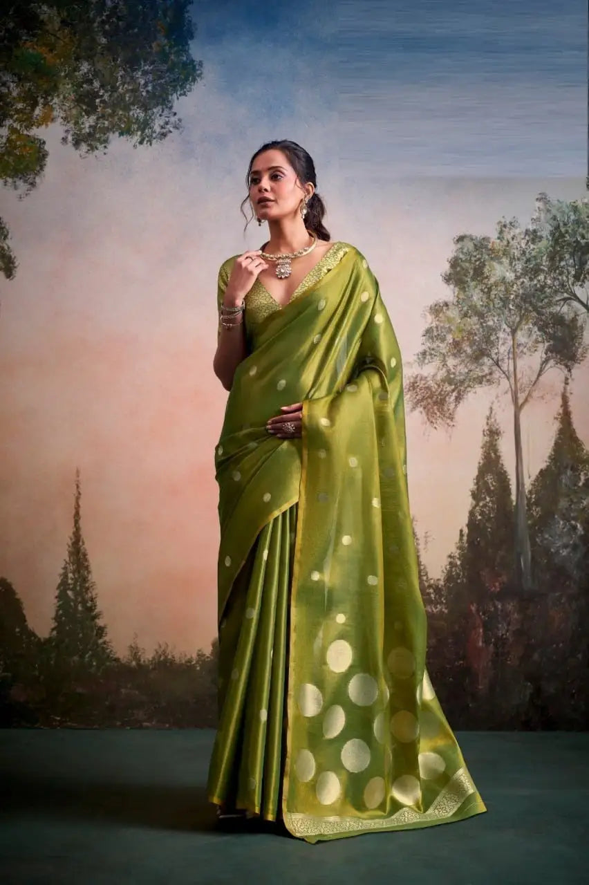 Woman wearing an elegant olive green silk saree with gold polka dot motifs.